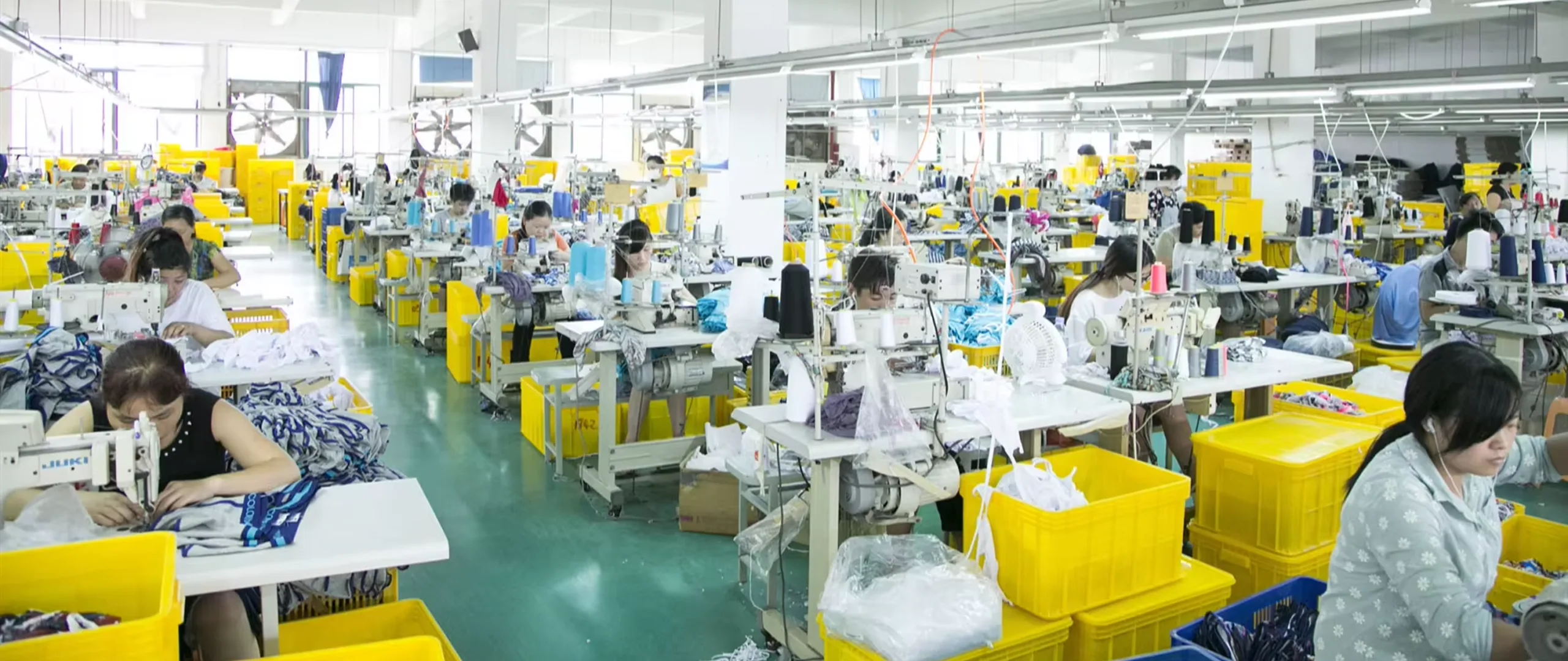 Rows of sewing stations across the LeelineBags production floor, operators at work under strip-lighting