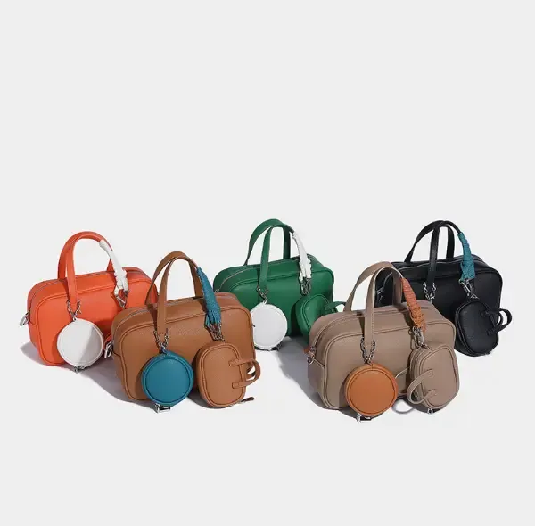 A row of small handbags in orange, tan, green, taupe and black, a matching round pouch set beside them
