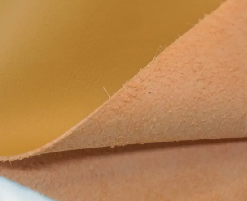 A close view of a fold in pale suede-backed microfiber, showing the brushed reverse side