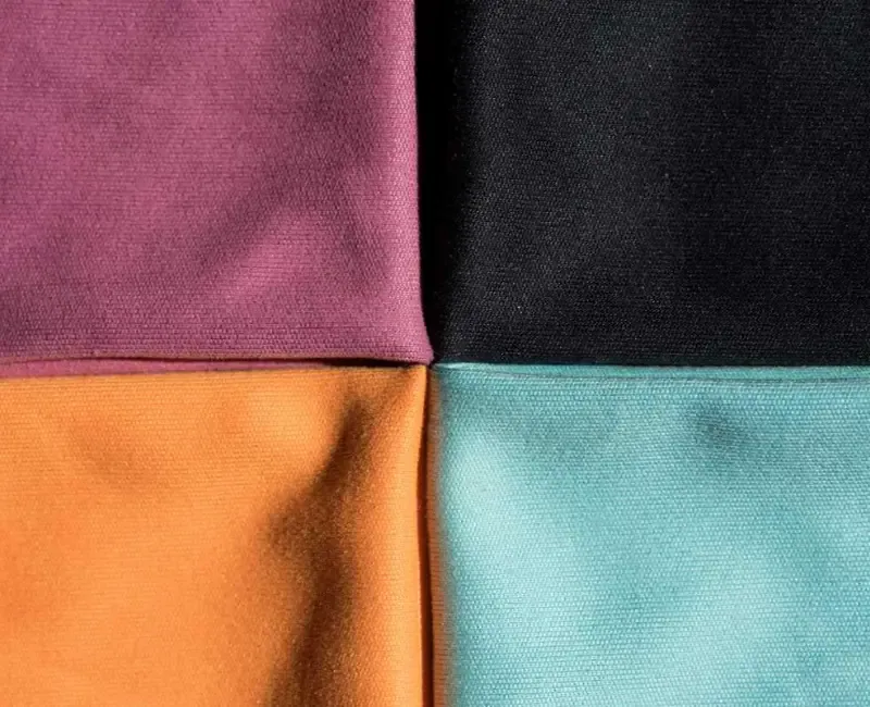 Four swatches of woven PVC-backed cloth ranged in purple, black, orange and teal