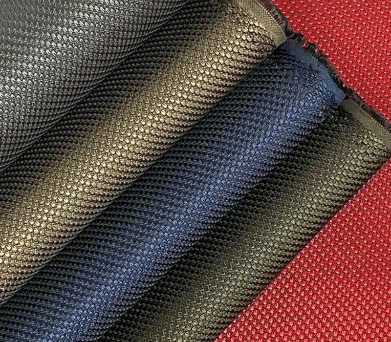 Several lengths of woven nylon fabric in navy, gunmetal, black and red, each threaded over a rod