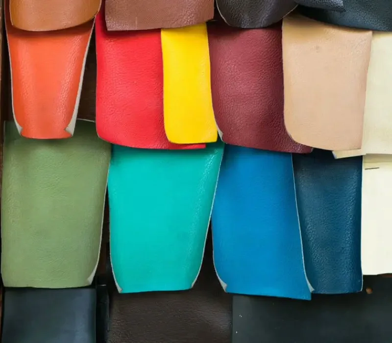 Rolls of PU-coated leather in blue, tan, burgundy, black and cream ranged across a pale surface