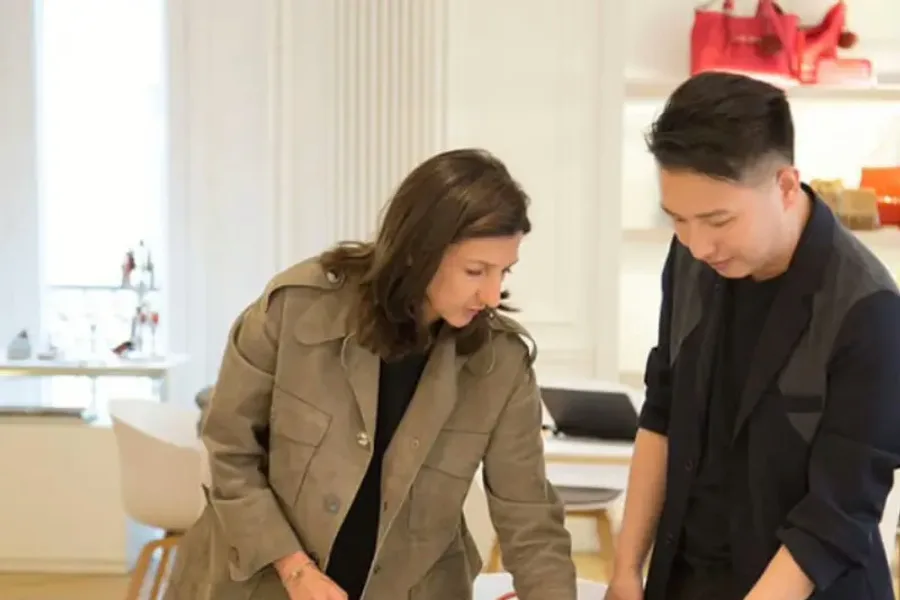 A brand buyer and a pattern maker reviewing cloth swatches and a colour card at the design table