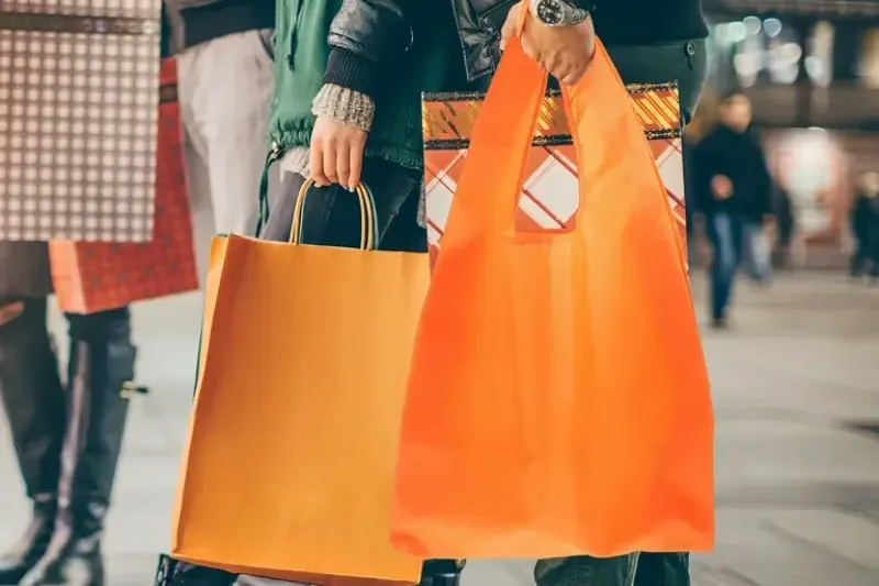 Shoppers on a street carrying a mix of printed and plain paper carrier bags