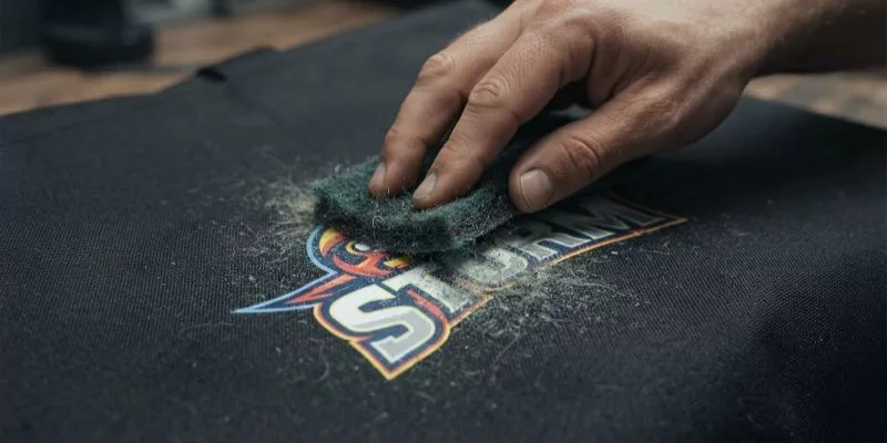 Abrasion resistance test on a screen-printed logo using a scrub pad.