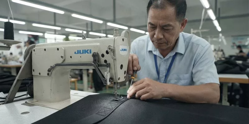 Factory manager adjusting a Juki walking-foot sewing machine for Box-X strap reinforcement.