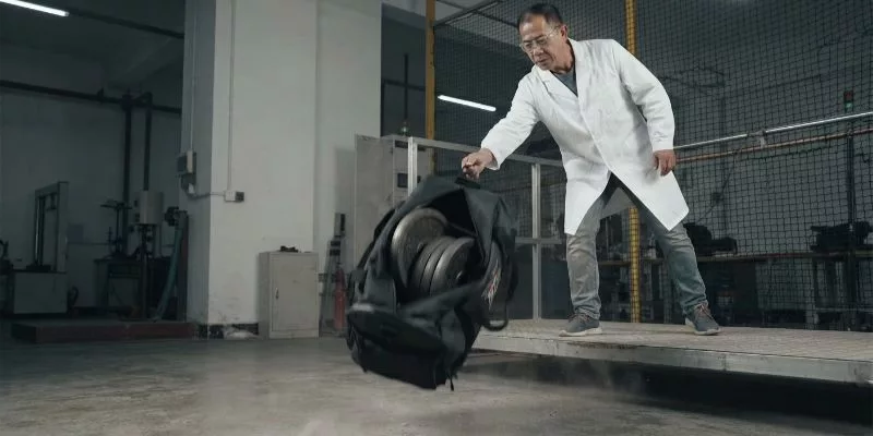QA manager drop-testing a custom sports bag loaded with 50 lbs of steel weights.