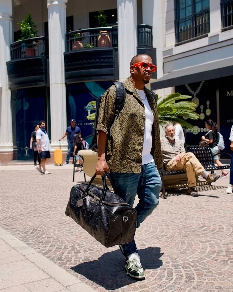 A black leather duffle carried by hand through a shopping arcade