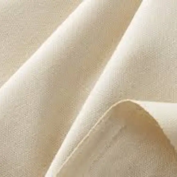 Undyed cotton canvas folded in soft diagonal waves, its plain weave visible