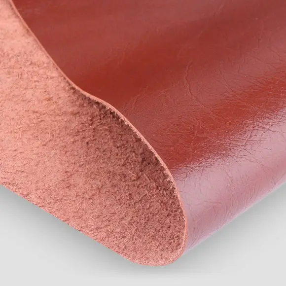 A folded panel of vegetable-tanned leather showing its grained face and fibrous cut edge