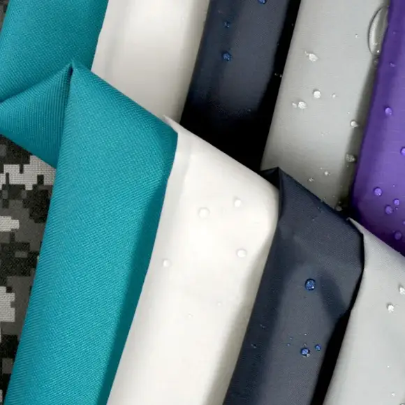 Folded lengths of nylon in teal, white, navy and grey, water beading on the coated faces