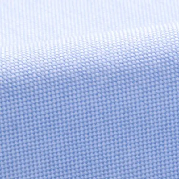 A close view of pale blue oxford cloth, the basket weave and its back coating picking up the light