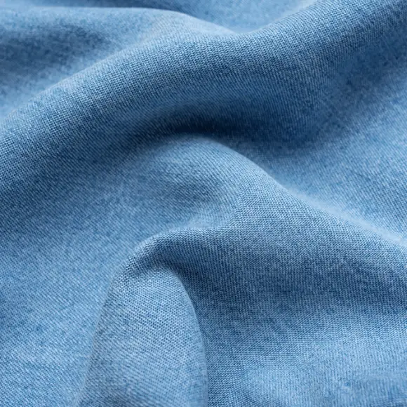 Soft pale-blue lyocell fabric draped in loose folds, its fine surface catching the light