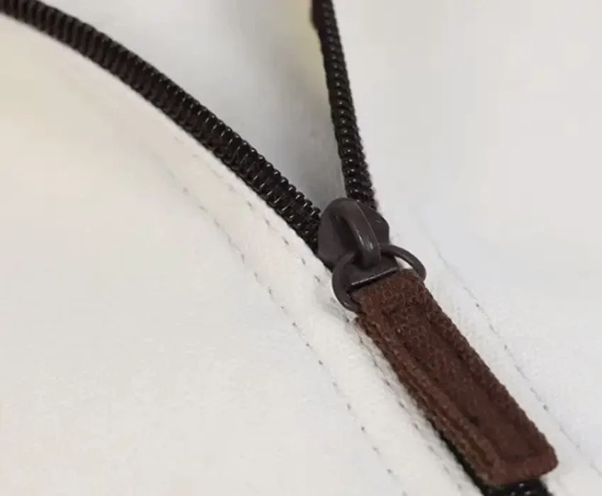 A close view of a full-length zip running down a cream cotton cover, the coil and the pull set into the cloth