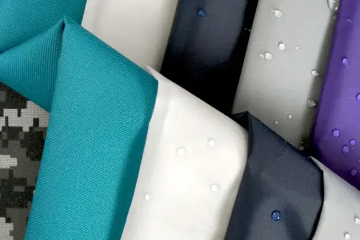 Folded lengths of nylon in teal, white, navy and grey with water beading on the coated faces