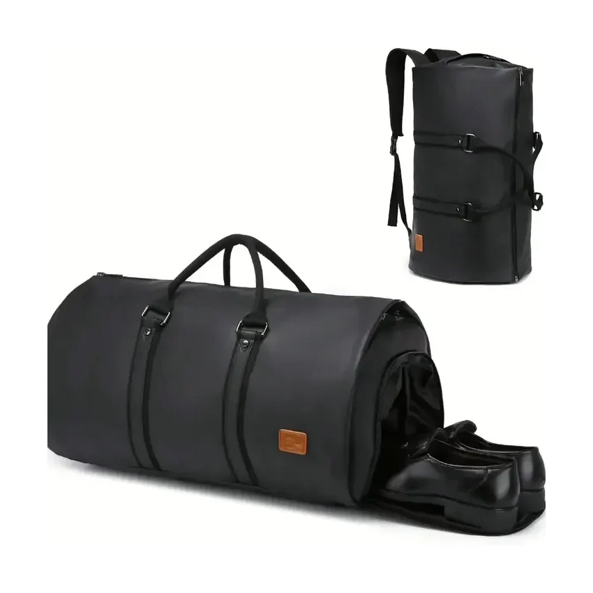 A black leather-look travel garment bag rolled shut on a carry handle, with a matching backpack behind it and a pair of shoes in the open end
