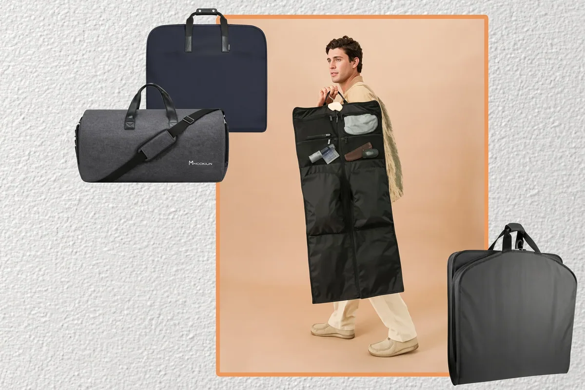 A grey garment bag carried over a shoulder, with a folded suit cover, a duffle and a weekender beside it