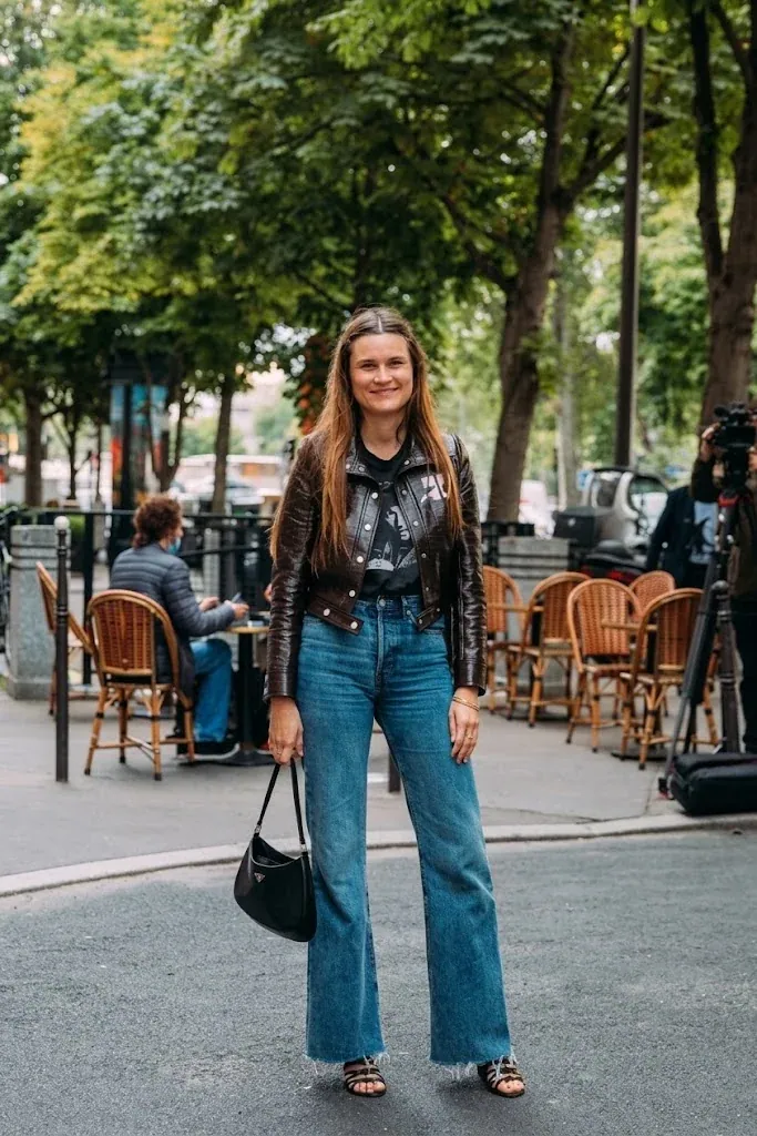 A black leather shoulder bag carried beside a street cafe terrace