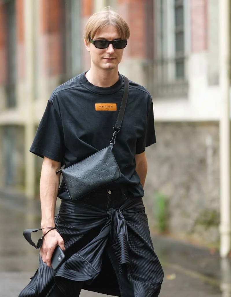 A black leather crossbody bag carried on the shoulder in the rain