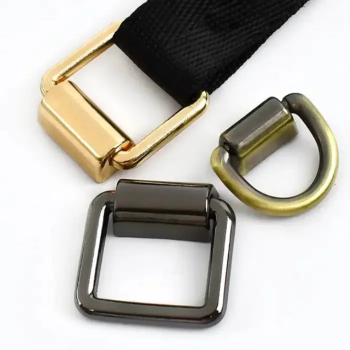 Three bag buckles in polished gold, gunmetal and antique brass, one threaded with black webbing