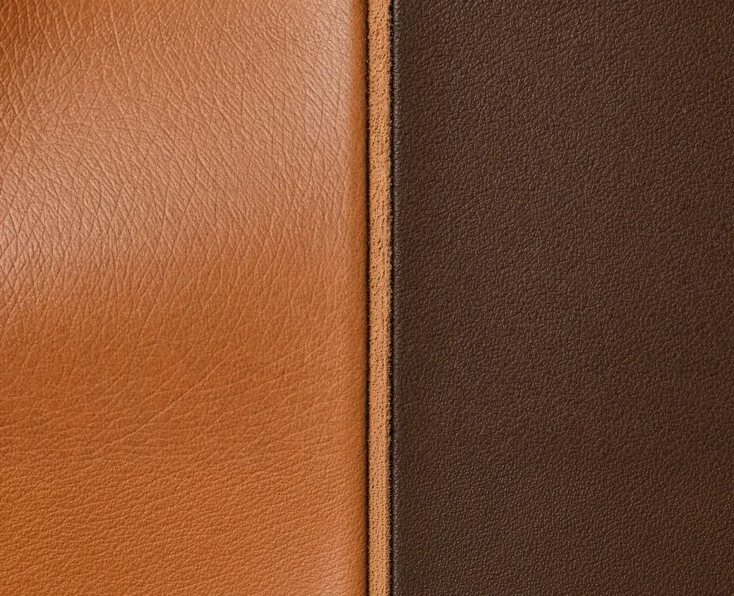 Two leather faces meeting at a cut edge, the tan full-grain face on the left and the darker sanded top-grain on the right, the fibrous underside showing along the join