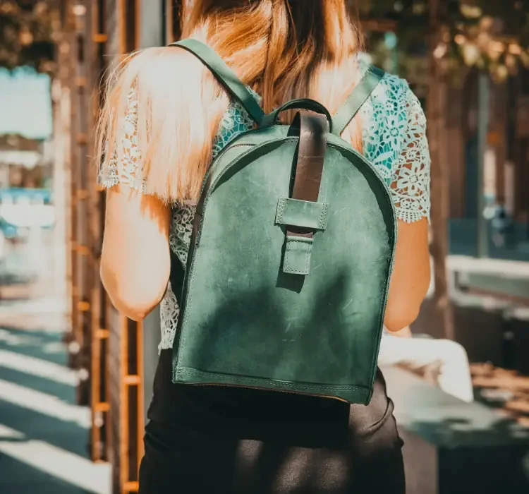 A person from behind wearing a deep green leather backpack over a lace top