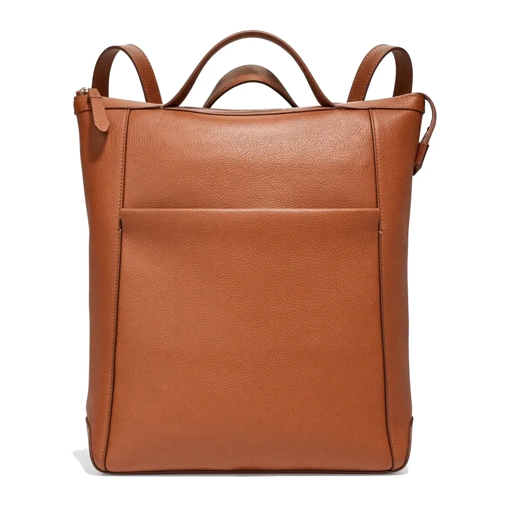 A tan leather backpack shown upright with a zipped top, a concealed front pocket panel and three carry straps — a top handle with a shoulder strap either side
