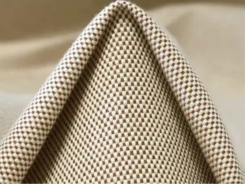 A folded length of natural cotton canvas fabric catching soft light against a pale background