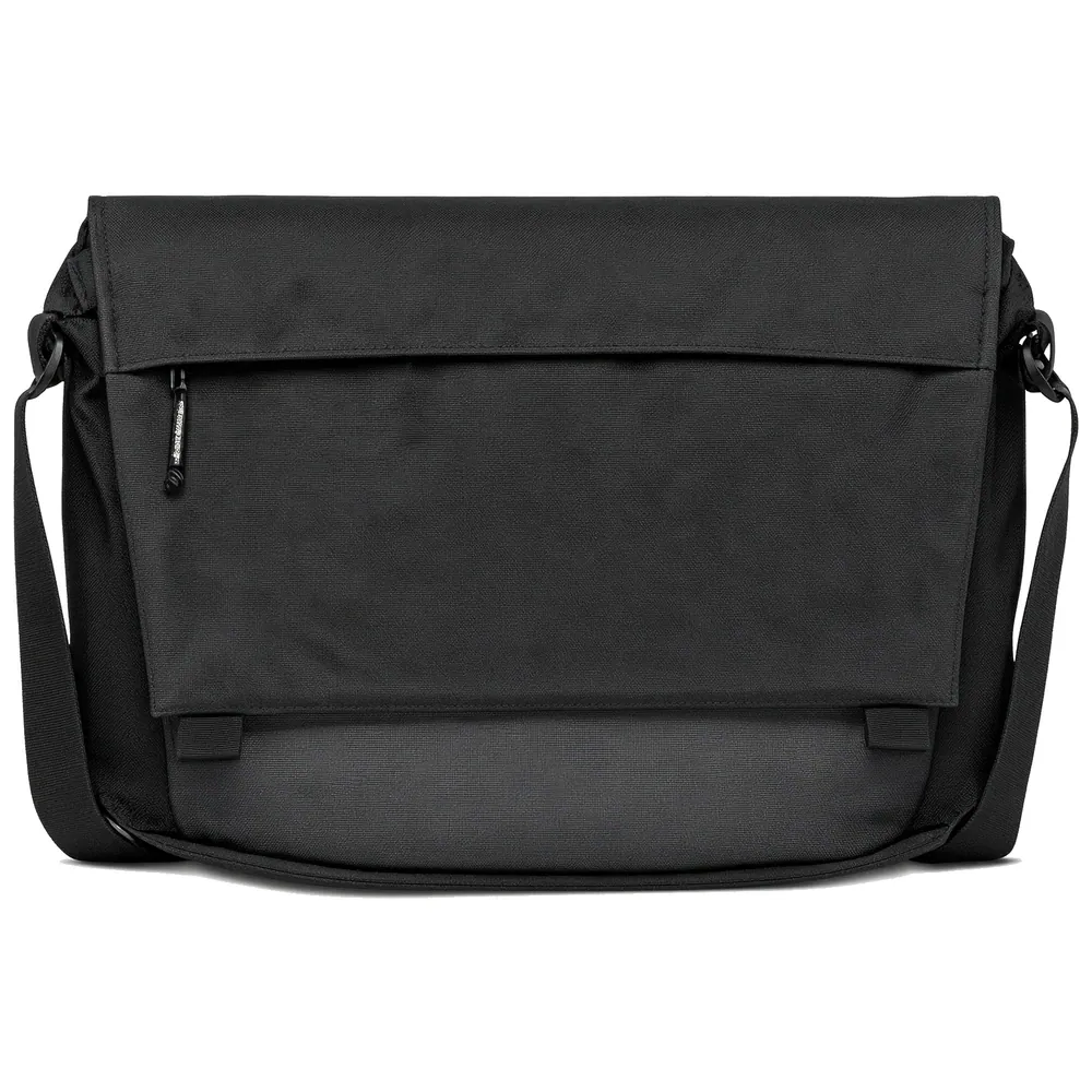 A black nylon messenger bag with a wide fold-over flap carrying a zip pocket on its face, on a long webbing strap