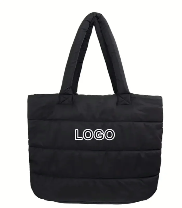 A black channel-quilted shopping tote with a woven handle and a plain centre panel for a logo