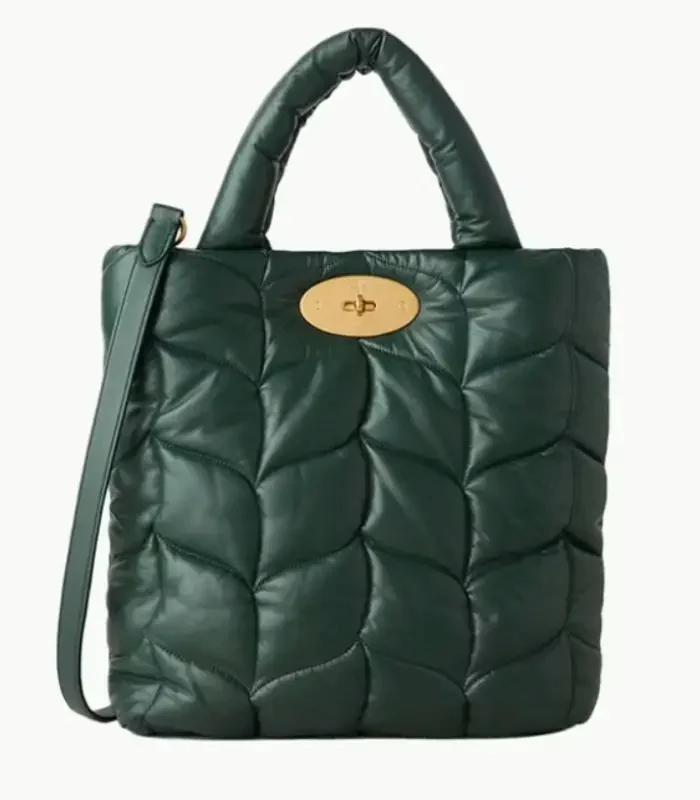 A deep-green quilted gift tote with a padded round handle and a gold turnlock