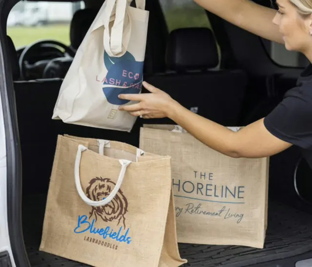 Branded reusable gift bags being handed through a car boot for a corporate gifting run