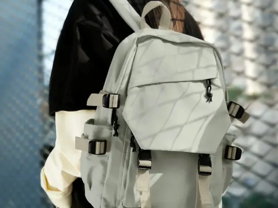 A senior school backpack hung from a hook, its front pocket, buckles and compression straps shown in close detail