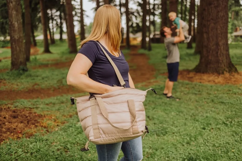A quilted beige tote carried across a park lawn