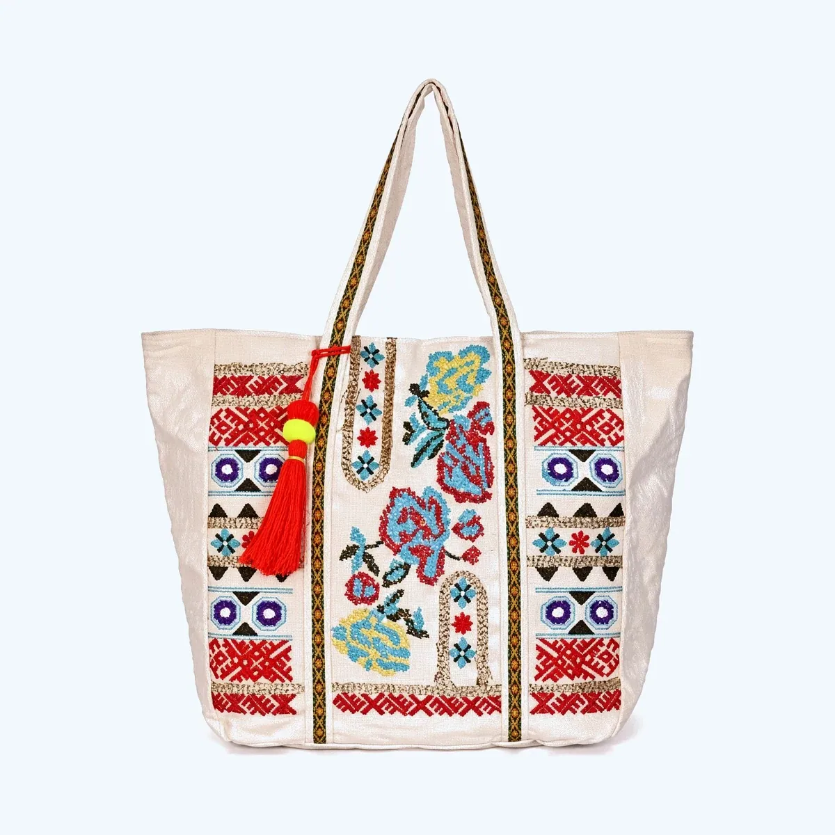 A cream canvas tote bag with dense embroidered floral and geometric panels