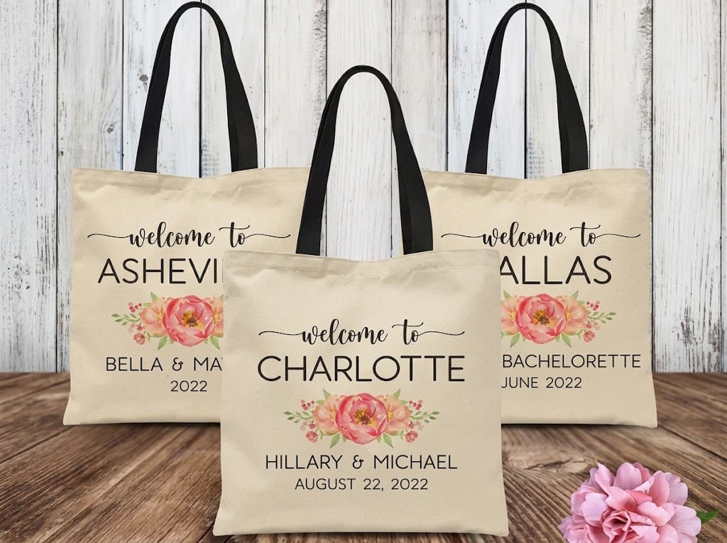 Three cream canvas totes printed with script lettering and a floral motif, personalised for a wedding party and a bachelorette weekend