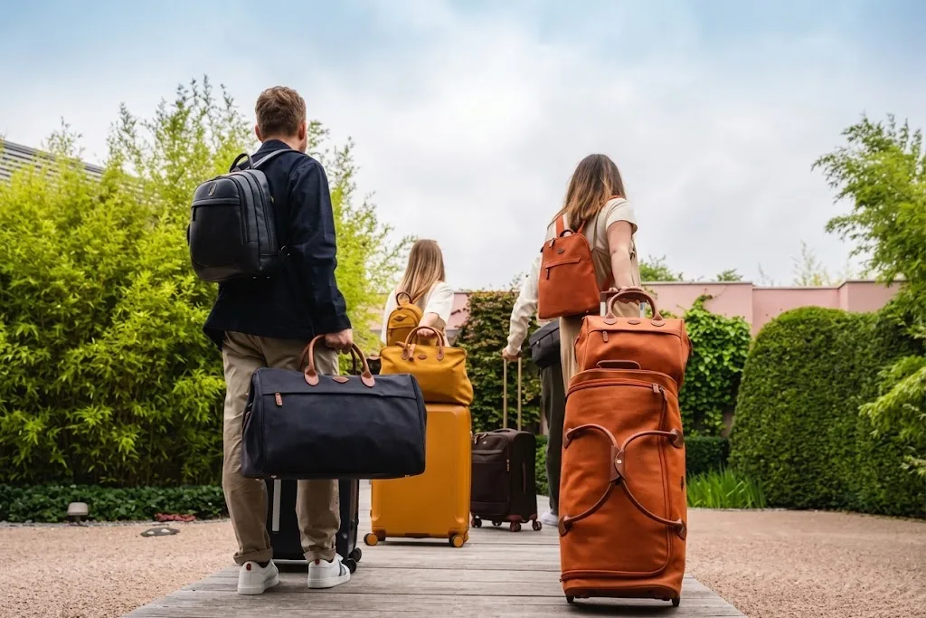 Three travellers walking an outdoor path, carrying a different travel bag apiece